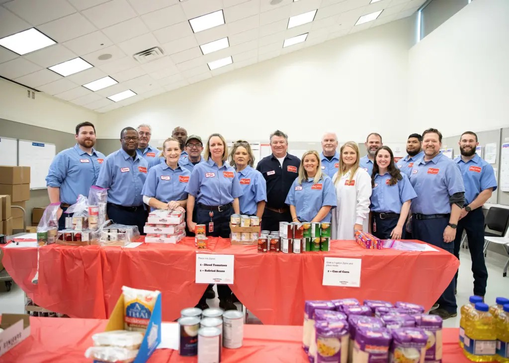 A group of Post Consumer Brands employees stand behind a table full of packed goods.