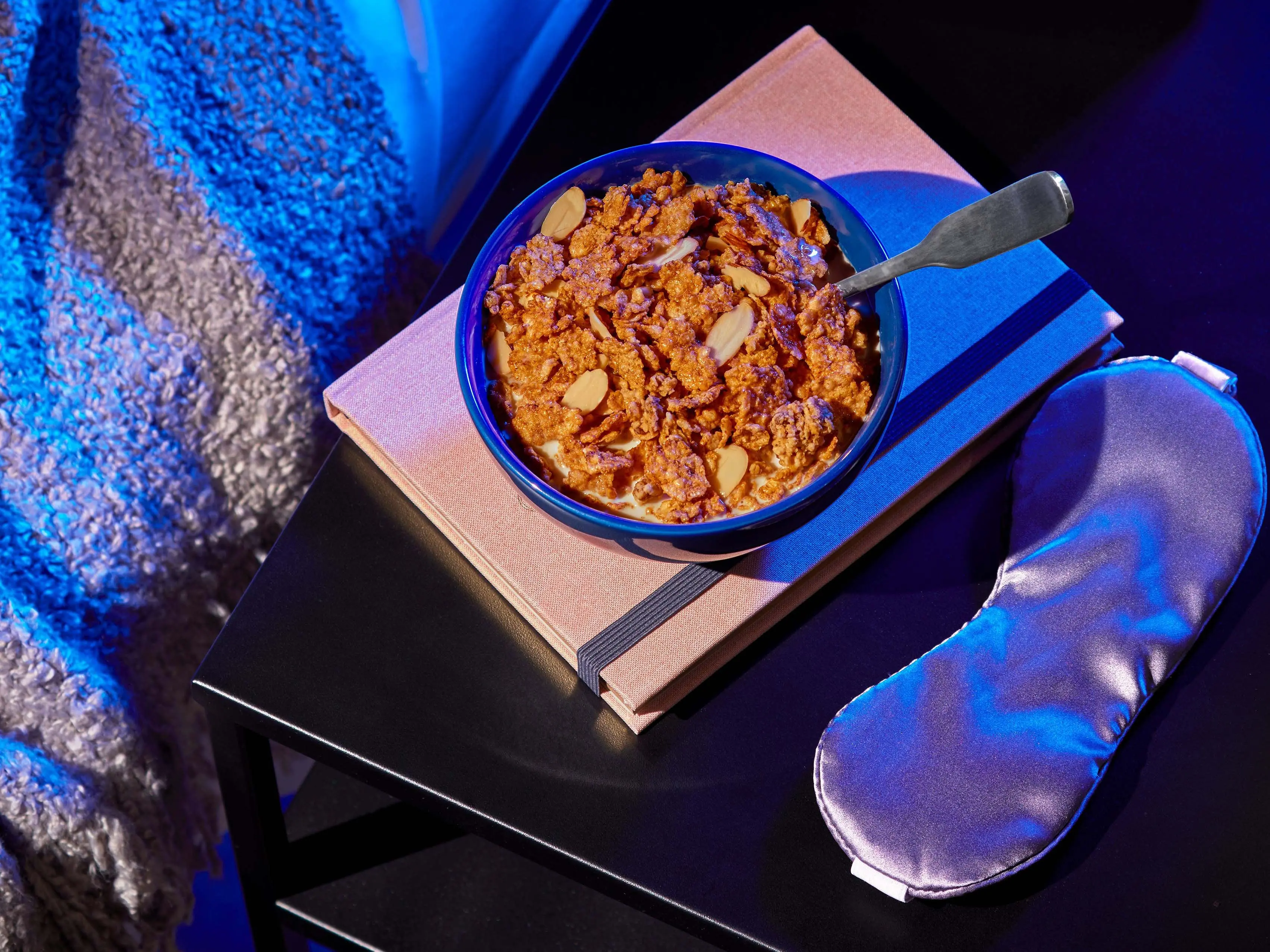 A bowl of sweet dreams cereal with eye covers and a blanket on either side.