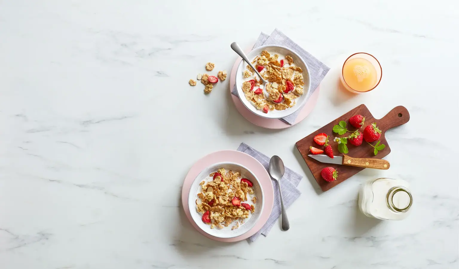 Bowls of Post cereal and strawberries on a countertop