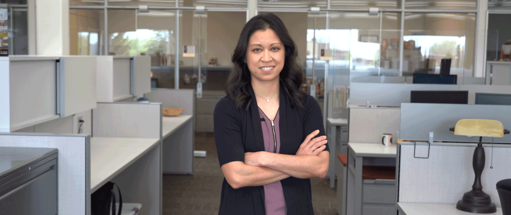 A woman smiles while standing in an office