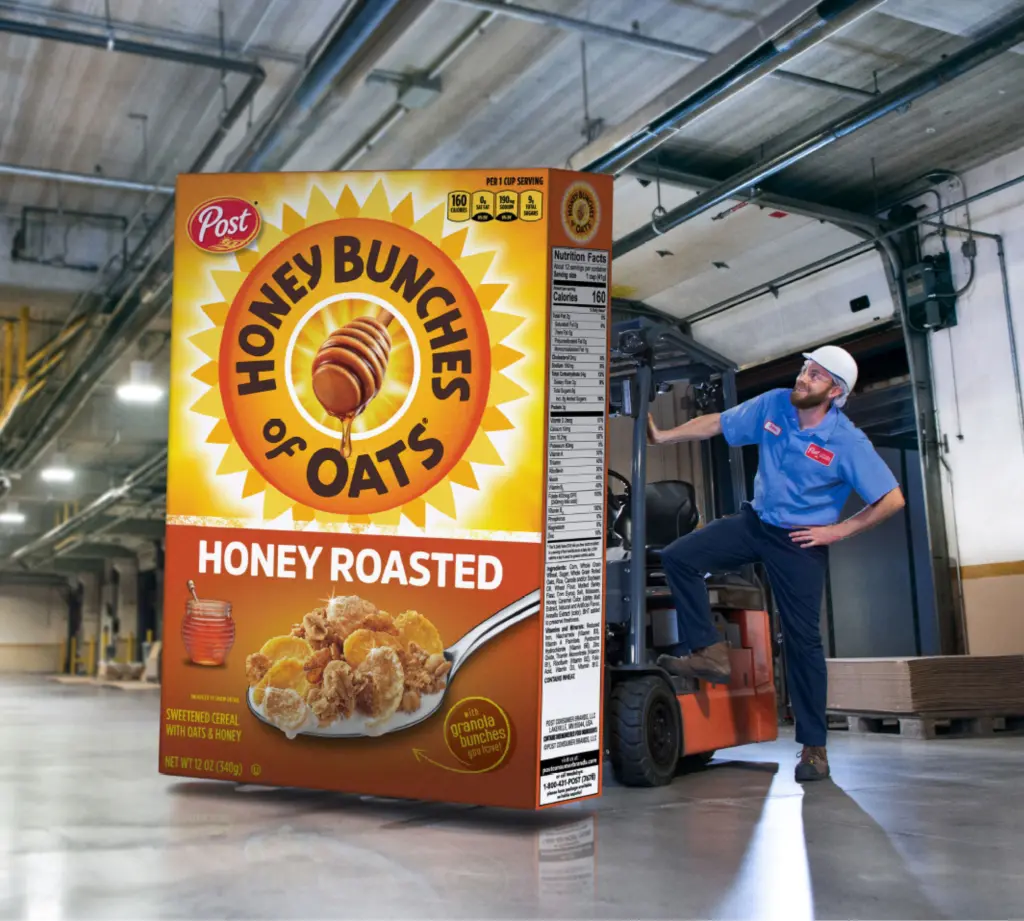 Post Consumer Brands manufacturing employee standing next to giant Honey Bunches of Oats cereal box