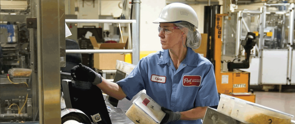 A woman in a hard hat holds a container.