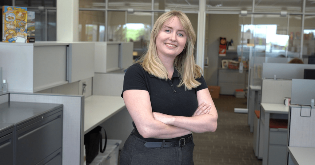 A woman stands for a photo in an office.