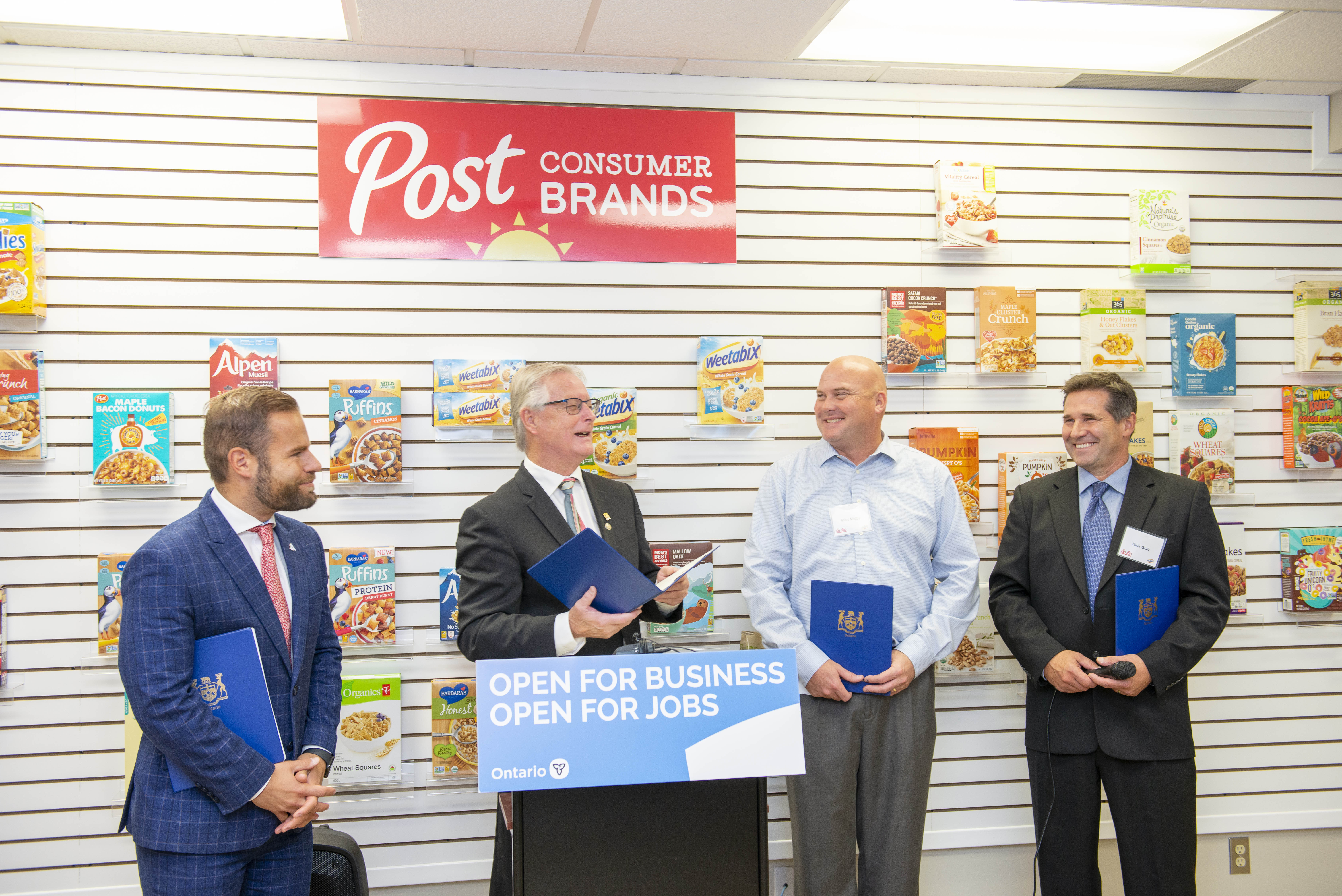 Four men standing at a podium to announce a grant for the Cobourg plant