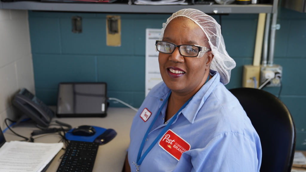 A Post employee in a hairnet sits in a chair