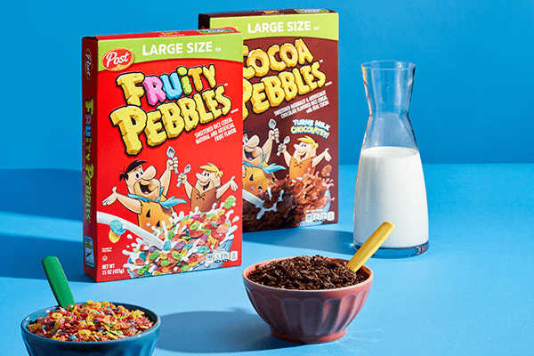 Boxes of Fruity PEBBLES and Cocoa PEBBLES cereal next to a carafe of milk and two cereal bowls