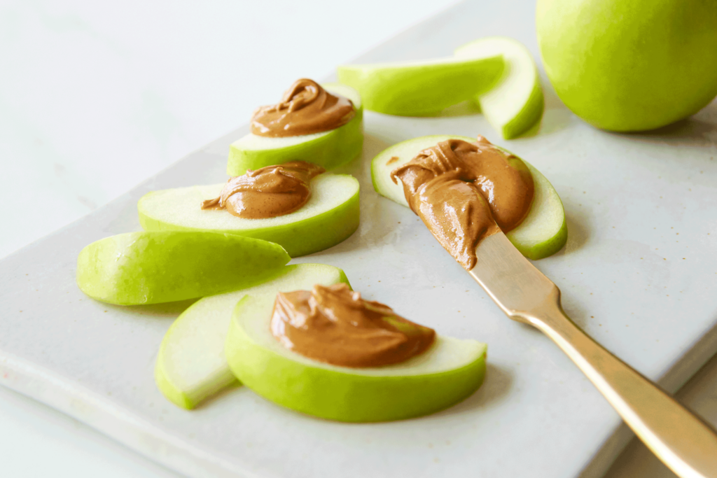 Peanut butter being put on apple slices.