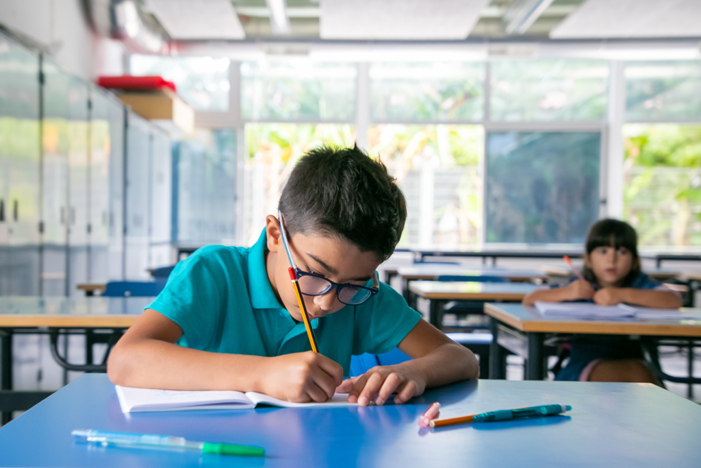 A child in a blue shirt writes in a notebook