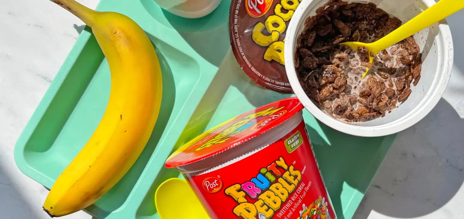 Fruity PEBBLES and Cocoa PEBBLES containers on a platter next to a banana