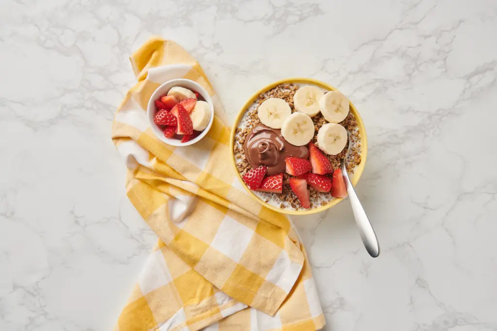 Grape-Nuts cereal topped with bananas, strawberries and hazelnut spread