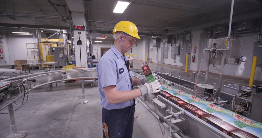 A Post Consumer Brands manufacturing employee inspecting a cereal box