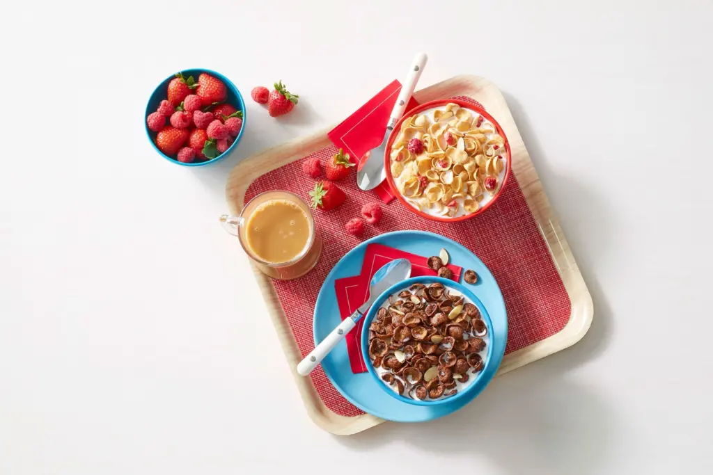 Bowls of Premier Protein cereal with bowls of fruit nearby.
