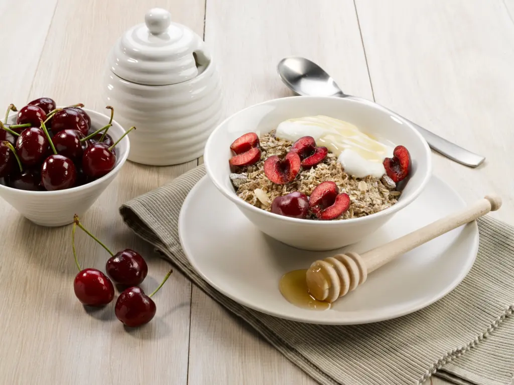 A bowl of Alpen Muesli with cherries, yogurt and honey