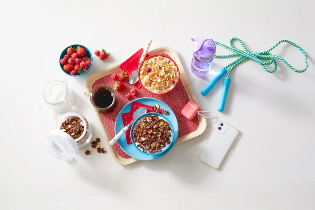 Bowls of Premier Protein cereal with a cup of coffee, a bowl of berries, and workout equipment