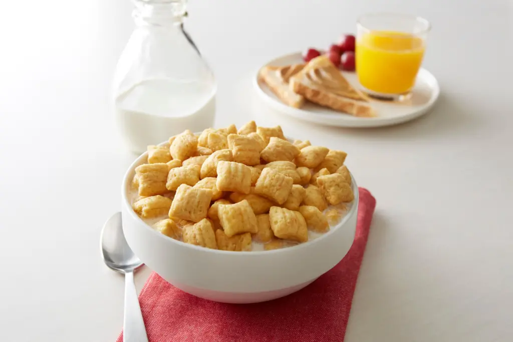 Puffins Peanut Butter cereal in a bowl with milk with other breakfast foods in the background